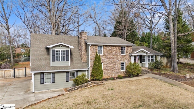 view of front of house with a chimney, roof with shingles, and fence