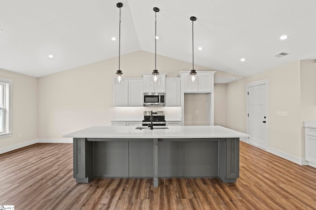 kitchen with an island with sink, wood finished floors, appliances with stainless steel finishes, white cabinets, and light countertops