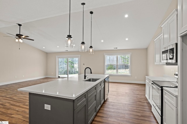 kitchen featuring gray cabinetry, a sink, stainless steel appliances, light countertops, and vaulted ceiling