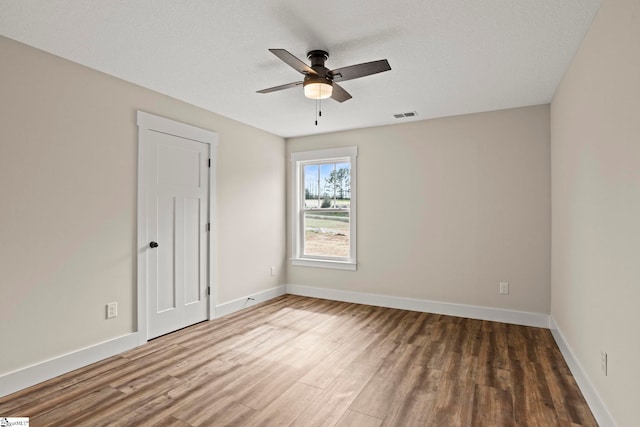 unfurnished room featuring visible vents, wood finished floors, baseboards, and ceiling fan