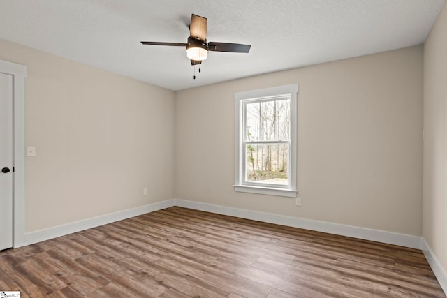 spare room with baseboards, a textured ceiling, wood finished floors, and a ceiling fan