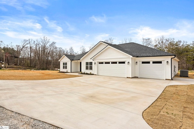 view of front of property with concrete driveway, cooling unit, a garage, and roof with shingles