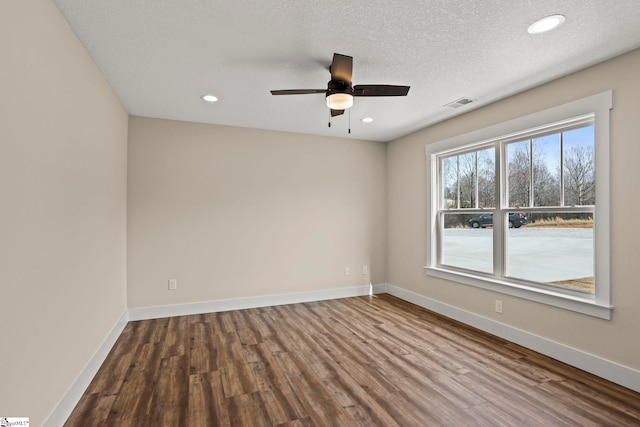 empty room featuring dark wood finished floors, visible vents, recessed lighting, and baseboards