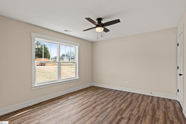 spare room featuring visible vents, a textured ceiling, baseboards, and wood finished floors