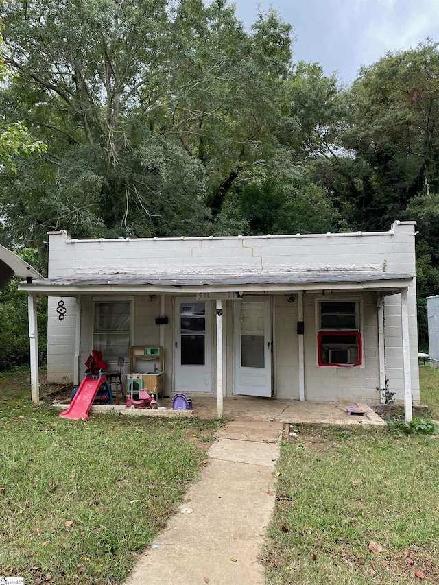 view of front of property with covered porch, concrete block siding, and a front yard