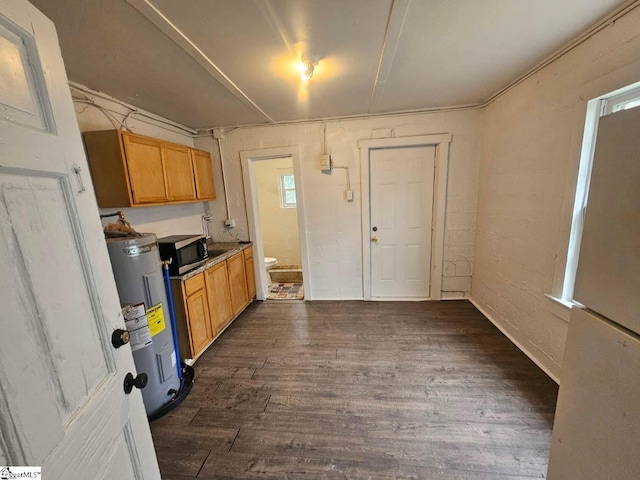 kitchen featuring stainless steel microwave, dark wood-style floors, and water heater