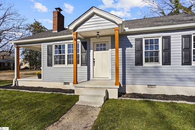 doorway to property featuring crawl space, a yard, roof with shingles, and a chimney