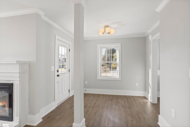 foyer entrance with a glass covered fireplace, crown molding, wood finished floors, and baseboards