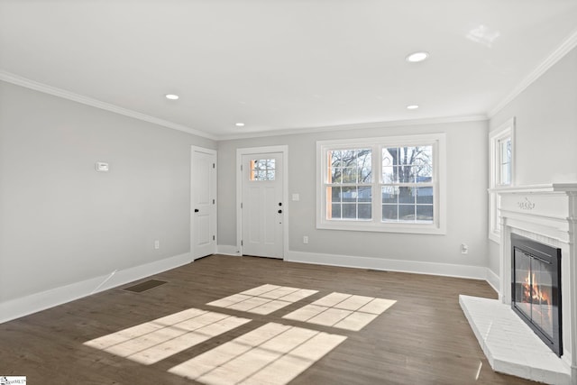 unfurnished living room featuring visible vents, baseboards, ornamental molding, wood finished floors, and a glass covered fireplace