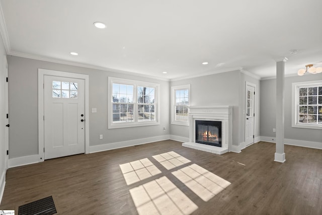 unfurnished living room with visible vents, ornamental molding, a glass covered fireplace, and wood finished floors