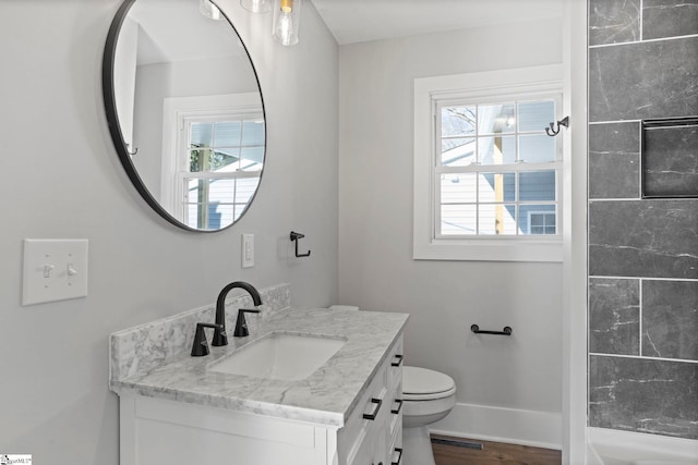 bathroom with baseboards, plenty of natural light, toilet, and vanity