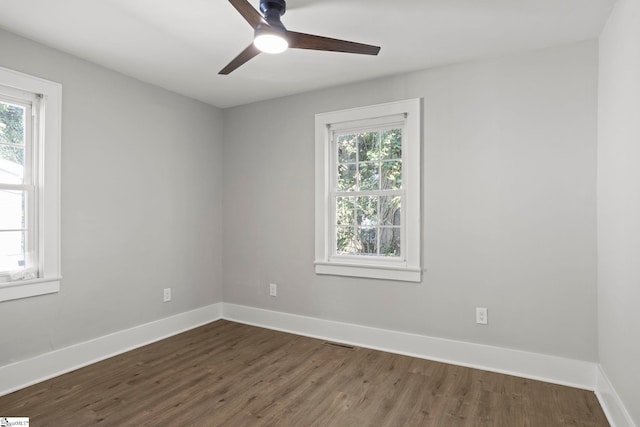 spare room featuring dark wood-style floors, a healthy amount of sunlight, and baseboards