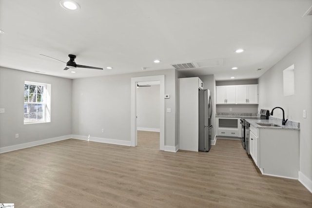 kitchen with a sink, open floor plan, white cabinetry, recessed lighting, and appliances with stainless steel finishes