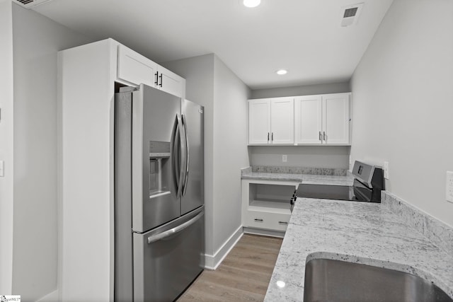 kitchen with visible vents, a sink, stainless steel appliances, light wood-style floors, and white cabinets