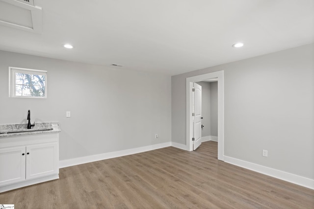 spare room featuring a sink, baseboards, light wood-style flooring, and recessed lighting