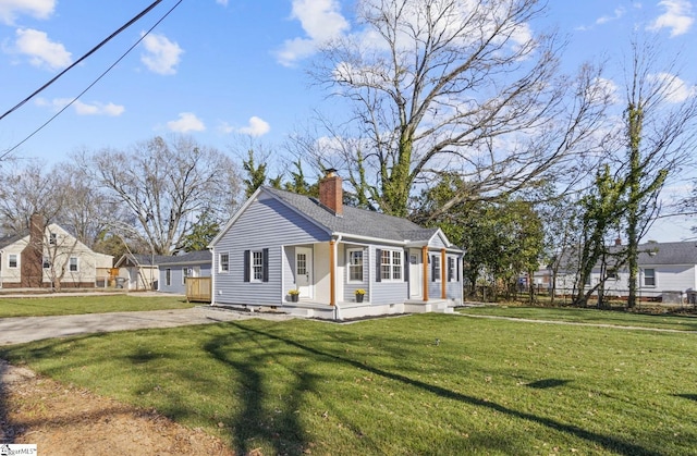 view of front of home featuring driveway, a chimney, a front yard, and fence