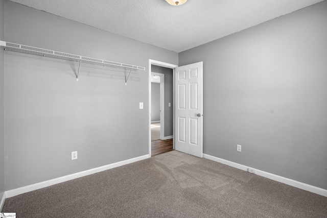 unfurnished bedroom featuring carpet flooring, a textured ceiling, and baseboards