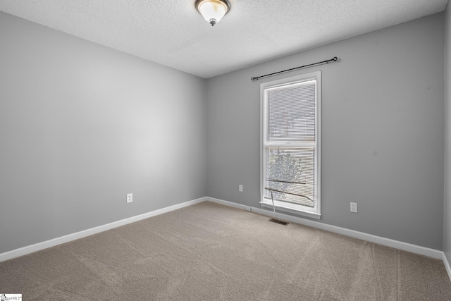 empty room with visible vents, a textured ceiling, baseboards, and carpet floors