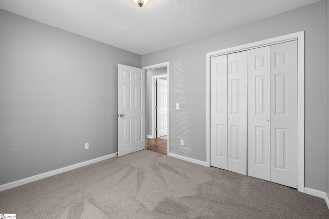 unfurnished bedroom with carpet flooring, baseboards, a closet, and a textured ceiling