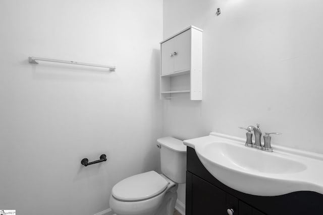 half bath with baseboards, toilet, and vanity