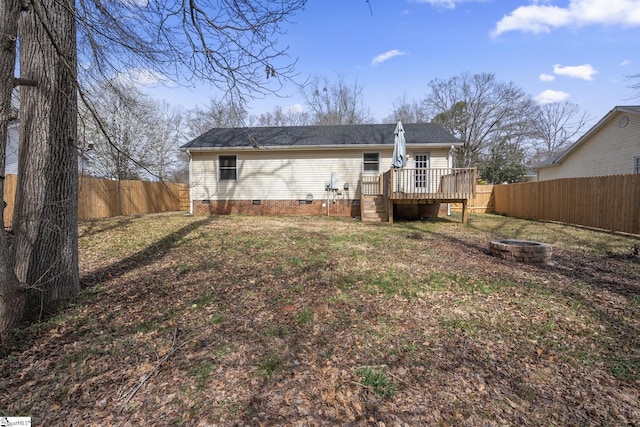 back of house featuring a fenced backyard, a yard, a fire pit, a wooden deck, and crawl space