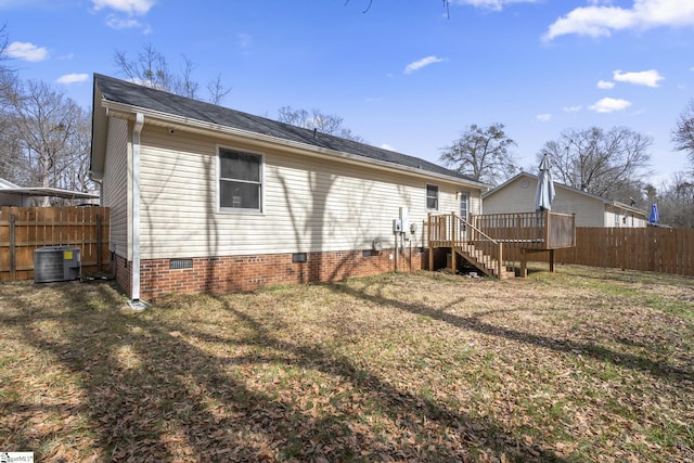 rear view of property with a lawn, fence, cooling unit, crawl space, and stairs