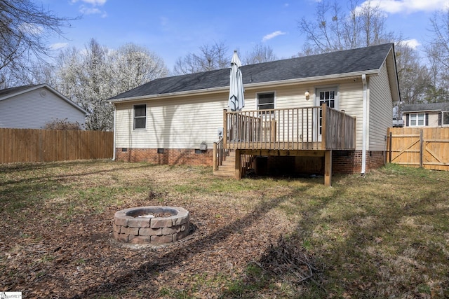 rear view of house with fence, an outdoor fire pit, crawl space, a deck, and a lawn