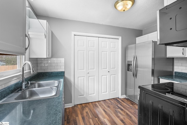 kitchen with a sink, dark wood-type flooring, black range with electric stovetop, white cabinetry, and dark countertops