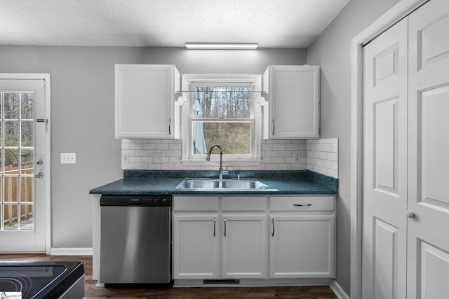 kitchen featuring dishwasher, dark countertops, white cabinetry, and a sink