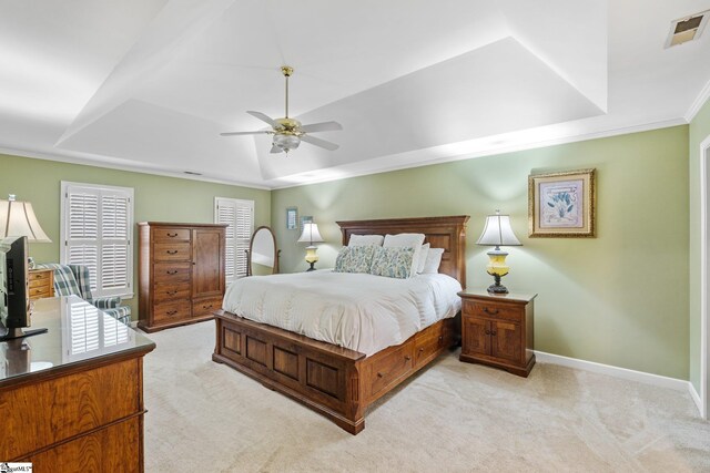 bedroom with visible vents, light colored carpet, and a raised ceiling