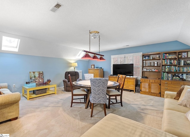 carpeted dining area featuring visible vents, vaulted ceiling with skylight, and a textured ceiling