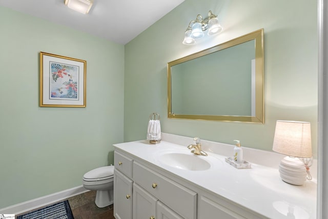 half bath featuring vanity, toilet, and baseboards