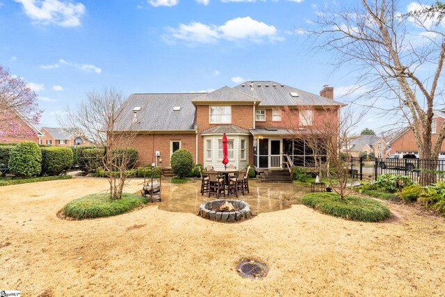 rear view of property featuring a patio, fence, an outdoor fire pit, a chimney, and brick siding