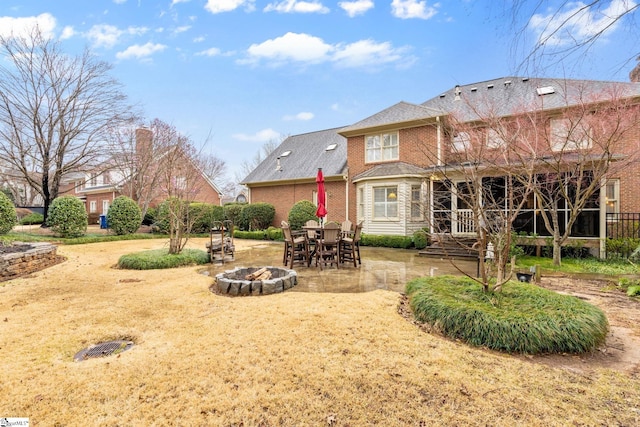 back of property featuring a patio, a fire pit, and brick siding