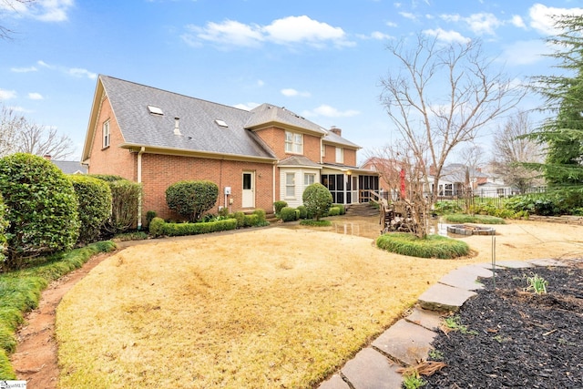 rear view of property featuring brick siding, fence, a chimney, a sunroom, and a patio area