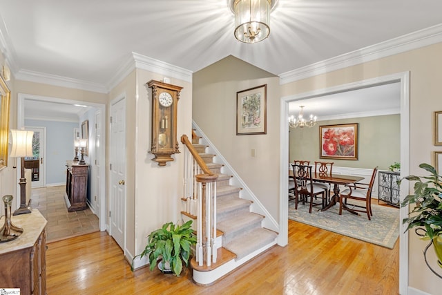 staircase with hardwood / wood-style flooring, a notable chandelier, baseboards, and ornamental molding