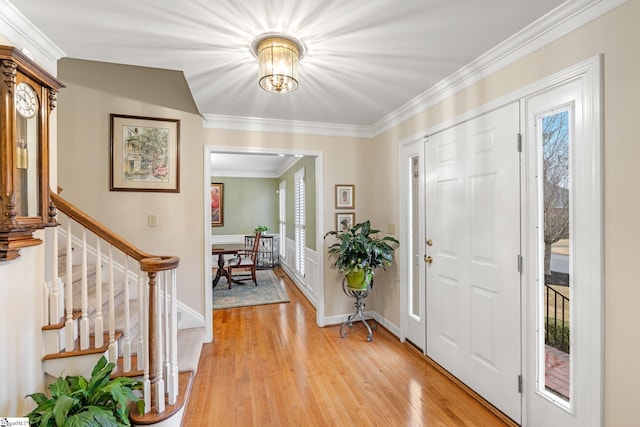 foyer with light wood-type flooring, stairway, baseboards, and crown molding