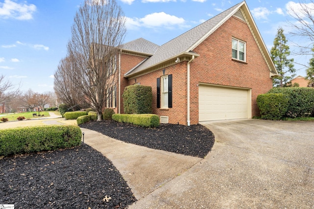 view of side of property with a garage, brick siding, driveway, and a shingled roof