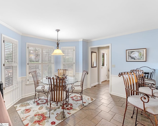 dining area featuring stone finish flooring, crown molding, and baseboards