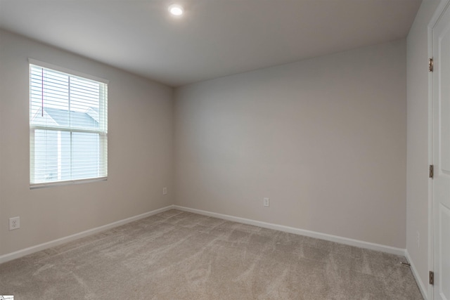 unfurnished room with baseboards, plenty of natural light, and light colored carpet