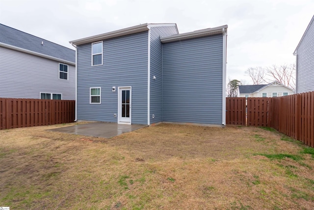 rear view of house featuring a patio, a yard, and a fenced backyard