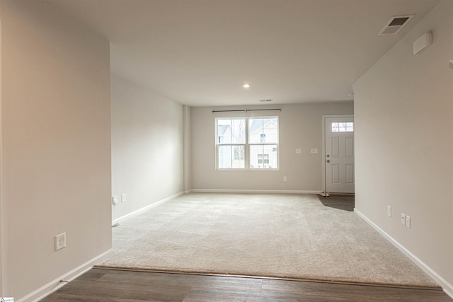 unfurnished room featuring wood finished floors, baseboards, visible vents, recessed lighting, and carpet flooring