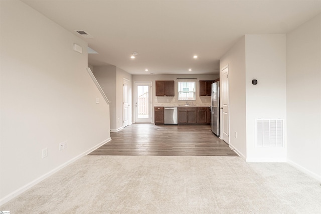 unfurnished living room featuring baseboards, visible vents, carpet floors, recessed lighting, and a sink