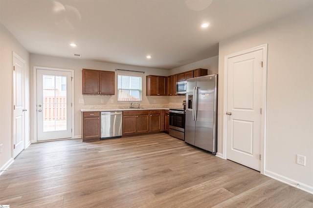 kitchen with light countertops, recessed lighting, light wood-style floors, stainless steel appliances, and a sink