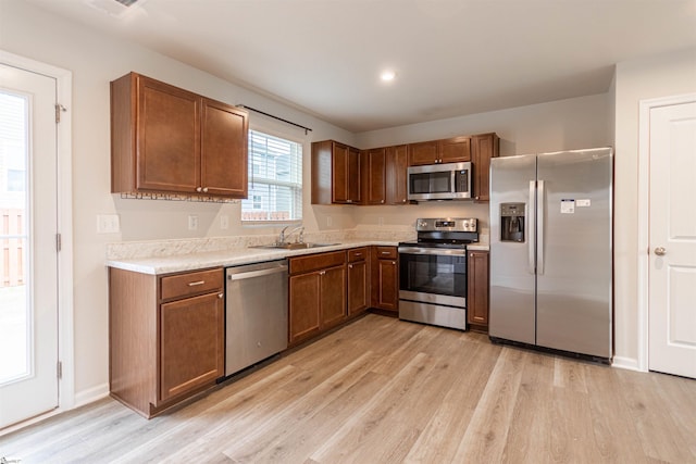 kitchen with light countertops, light wood-style floors, appliances with stainless steel finishes, and a sink