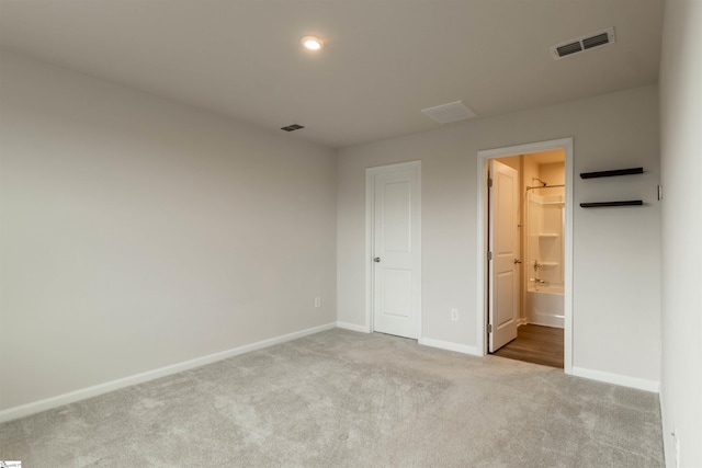 unfurnished bedroom featuring visible vents, carpet floors, baseboards, and ensuite bath