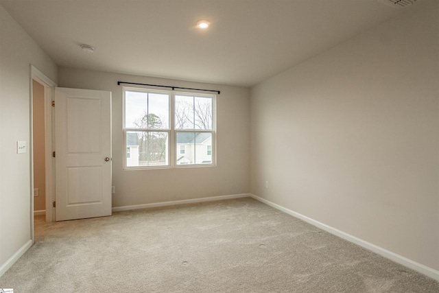 unfurnished room featuring visible vents, light colored carpet, and baseboards