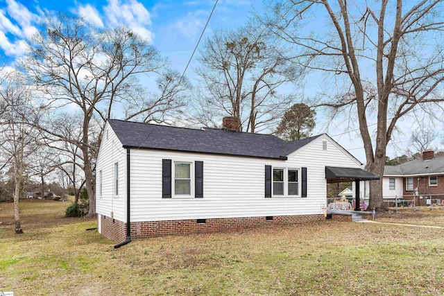 view of front facade with a carport, crawl space, a front lawn, and a chimney