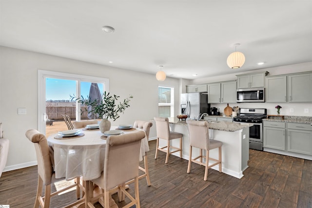 kitchen featuring a kitchen island with sink, dark wood-style flooring, and appliances with stainless steel finishes