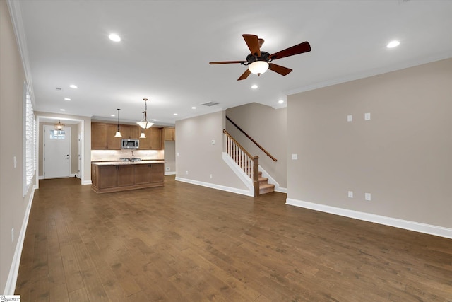 unfurnished living room featuring dark wood-style floors, baseboards, recessed lighting, ceiling fan, and stairs